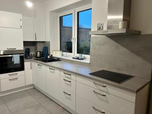 une cuisine avec des placards blancs et une grande fenêtre dans l'établissement Stylische Wohnung mit Garten im Zentrum, à Neumünster