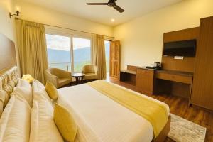 a hotel room with a bed and a large window at The Kempty Osasis - A Boutique Resort With Scenic Mountain View in Mussoorie in Mussoorie