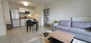 a living room with a couch and a table and a kitchen at Cosy Appartement proche Bordeaux Proche centre ville in Villenave-dʼOrnon