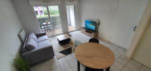 a living room with a couch and a table and a television at Cosy Appartement proche Bordeaux Proche centre ville in Villenave-dʼOrnon