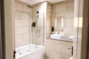 a bathroom with a shower and a tub and a sink at Mere Court Hotel in Knutsford