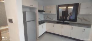 a kitchen with white cabinets and a person in a mirror at Villa calme in Taguermess