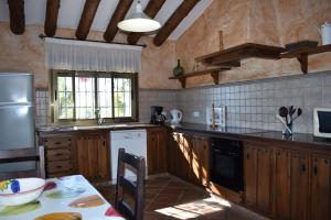 a kitchen with wooden cabinets and a table and a window at Finca Lagarillo with private Pool in Cómpeta