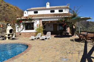 a house with a pool and chairs and an umbrella at Finca Lagarillo with private Pool in Cómpeta
