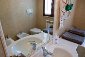 un bagno con lavandino, WC e specchio di Casa della Zia a Marotta