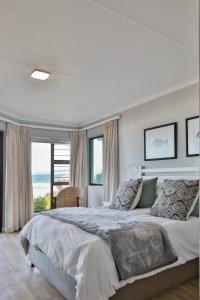 a white bedroom with a large bed and a window at Picnic Rock Seaside Accommodation in Keurboomstrand
