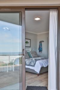 a bedroom with a bed and a sliding glass door at Picnic Rock Seaside Accommodation in Keurboomstrand