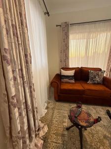 a living room with a couch and a window at Waridi is a modern, cosy penthouse in Mtwapa town in Mtwapa