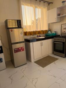 a kitchen with a refrigerator and a sink at Waridi is a modern, cosy penthouse in Mtwapa town in Mtwapa