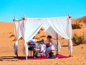 a woman sitting at a table in the desert at Super Luxury camp in Merzouga +29 photos