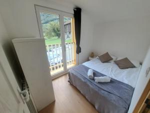ein Schlafzimmer mit einem Bett und einem großen Fenster in der Unterkunft Chalet Bois 6 personnes Sauna et Gym in Bellecombe