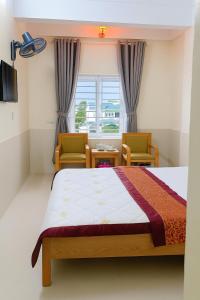 a bedroom with a bed and two chairs and a window at Phương Phương 2 Hotel in Ha Tinh