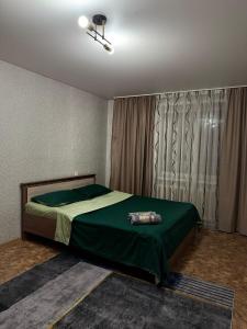 - une chambre avec un lit doté de draps verts et une fenêtre dans l'établissement Однокомнатая квартира, à Kökşetaw