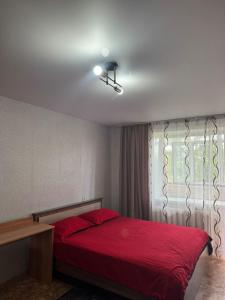 une chambre avec un lit rouge et une fenêtre dans l'établissement Однокомнатая квартира, à Kökşetaw