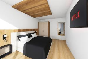 a bedroom with a black and white bed and a tv at PUREALPS Apartment - Opening December 2025 in Schwendberg