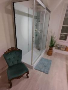 une salle de bain avec douche et une chaise verte dans l'établissement L'envol, à Germond