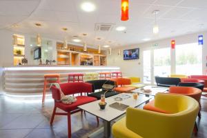 een restaurant met kleurrijke stoelen en tafels en een bar bij Kyriad La Rochelle Centre - Les Minimes in La Rochelle