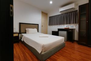 a bedroom with a large white bed and a desk at Watermelon Hotel in Miri