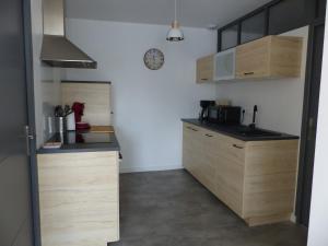 une cuisine avec des armoires en bois et une horloge au mur dans l'établissement Appartement cozy, à Pleine-Fougères 9 autres photos