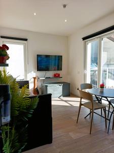 een woonkamer met een tv en een tafel en stoelen bij Orelli House - TriLocal Superior "2 Bedrooms & 2 Bathrooms " in Lissone