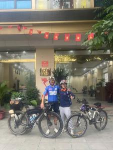 twee mensen staan met hun fietsen voor een gebouw bij Thăng Long Hotel Thanh Hoá in Thanh Hóa