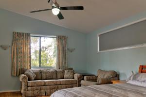 a bedroom with a couch and a bed and a window at Lockhart Leafy Cottage - walk to Mollymook Beach in Mollymook