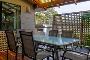 a table and chairs on a patio with a fence at Lockhart Leafy Cottage - walk to Mollymook Beach in Mollymook