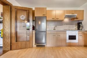 a kitchen with wooden cabinets and a stainless steel refrigerator at Panorama Ferienwohnung Tschengla in Bürserberg