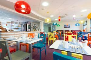 a restaurant with brightly colored tables and chairs at Hôtel Confort La Rochelle Centre les Minimes in La Rochelle