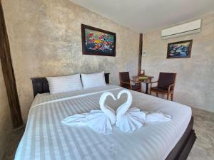 - une chambre avec un lit et une serviette en forme de cœur dans l'établissement ขวัญใจปราณ รีสอร์ท, à Ban Pak Nam Pran