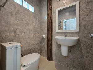 une salle de bain avec des toilettes blanches et un lavabo dans l'établissement ขวัญใจปราณ รีสอร์ท, à Ban Pak Nam Pran