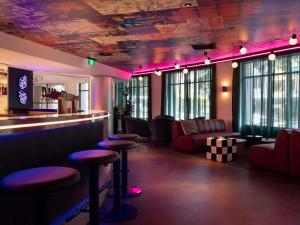 Un bar con iluminación violeta y taburetes en una habitación. en ibis Styles Sydney Central, en Sídney