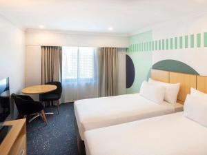 シドニーにあるibis Styles Sydney Centralのベッド2台とテーブルがあるホテルの部屋