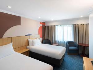 シドニーにあるibis Styles Sydney Centralのベッド2台と椅子があるホテルの部屋