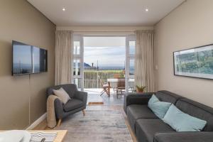 ein Wohnzimmer mit Sofa und Fernseher in der Unterkunft Dorian Place Oceanview Getaway in Simon’s Town in Murdoch Valley