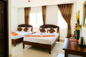 a hotel room with two beds and a desk at Phúc Lộc Hotel Ninh Bình in Ninh Binh