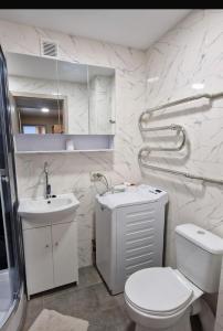 a white bathroom with a toilet and a sink at Pas Dianą 1 aukštas in Jurbarkas