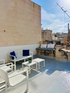 a balcony with white chairs and tables on a building at Carmelita Valletta in Valletta