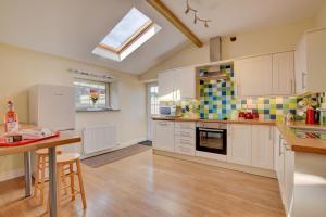 Una cocina grande con gabinetes blancos y un tragaluz. en Brynheulwen, en Llanilar