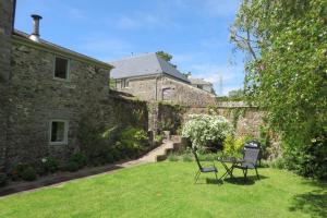 a garden with two chairs and a table in front of a building at Bovey Cottage in Broadhempston