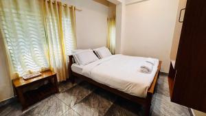 a bedroom with a bed with white sheets and a window at Nila Inn Thampanoor in Trivandrum