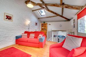 a living room with a red couch and two chairs at Bovey Cottage in Broadhempston