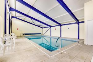 a large indoor swimming pool with blue beams at Bovey Cottage in Broadhempston +5 photos