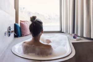 a woman sitting in a bath tub looking out a window at Seehotel Einwaller - adults only in Pertisau +92 photos