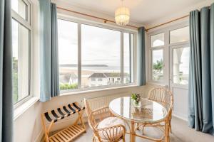 a dining room with a table and chairs and windows at Francis Cottage in Woolacombe