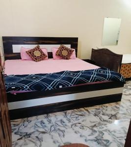 a bedroom with a bed with pink pillows on it at Lakshman Guest House Ayodhya in Jāmb