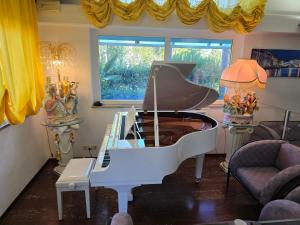 a white piano in a living room with a couch at Hotel Vina De Mar in Lignano Sabbiadoro +64 photos