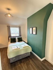 a bedroom with a bed with a green wall at Modern & Spacious, 4BR 4Bath, Parking, Sleeps 8 in Coventry +5 photos