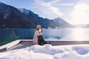 a woman sitting on the edge of a boat in the snow at Seehotel Einwaller - adults only in Pertisau