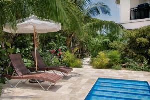 two chairs and an umbrella next to a swimming pool at Karana Studio 1 - K1 in Long Bay Hills